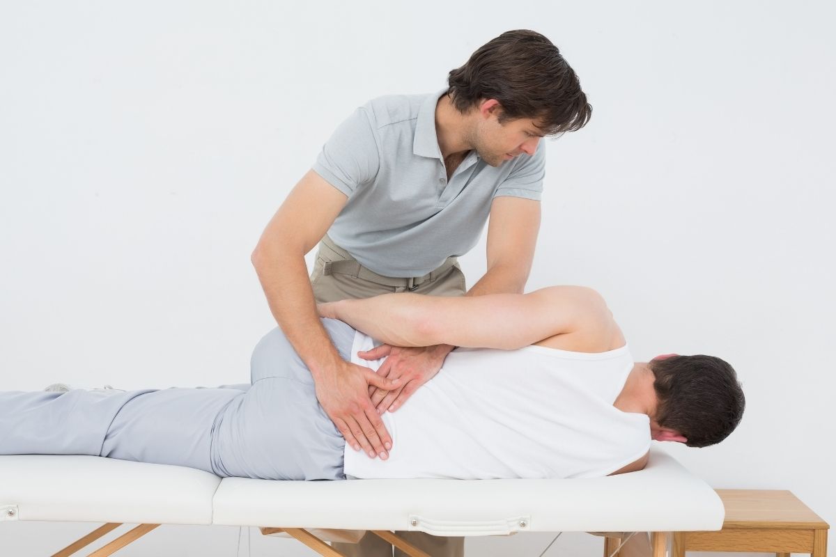 Physiotherapeut führt orthopädische Behandlung am unteren Rücken eines Patienten durch