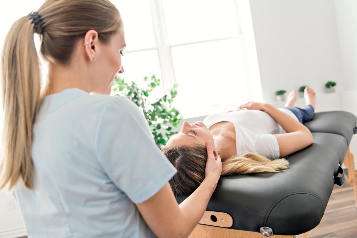 Physiotherapeutin behandelt Patientin auf Therapieliege in moderner Praxis